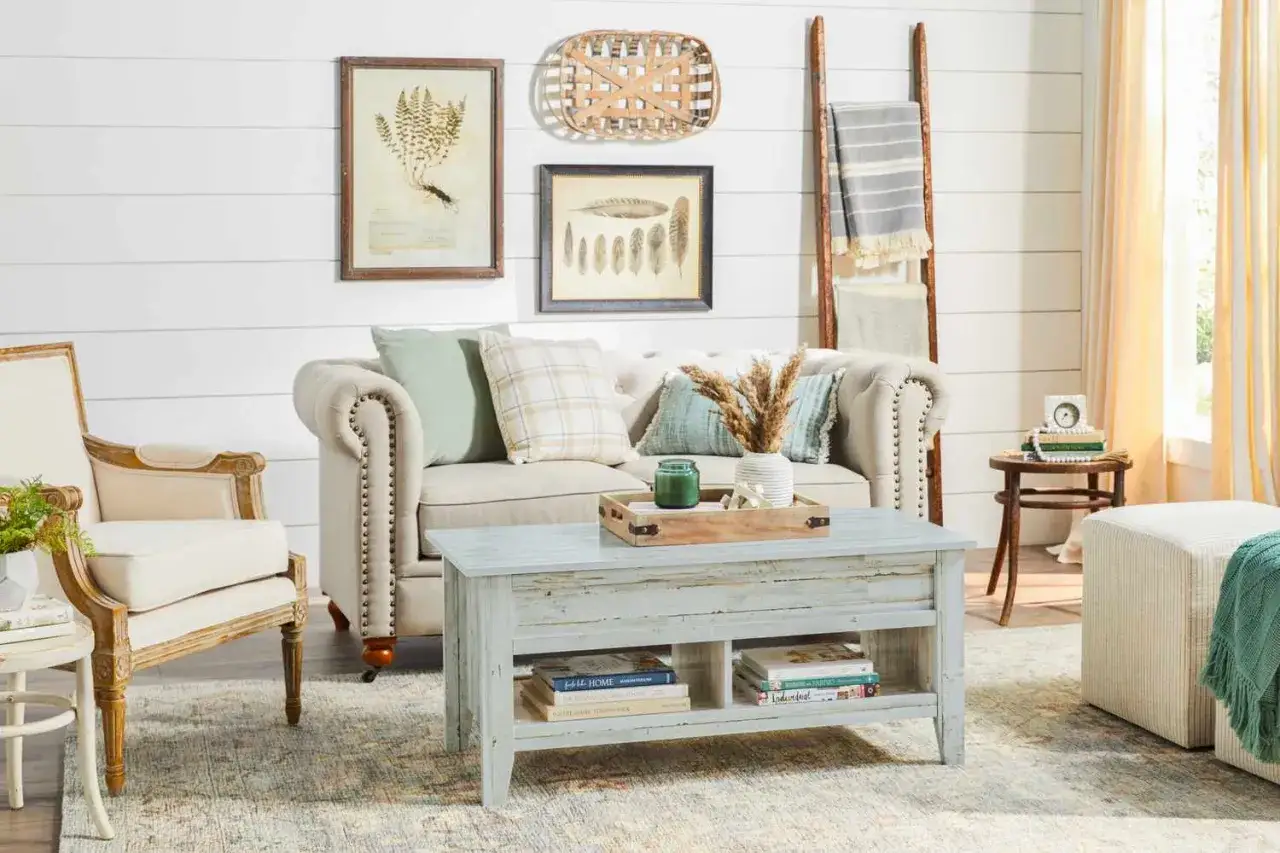 En mysig soffgrupp med shabby chic inredning. En sliten soffa, en f&aring;t&ouml;lj och ett soffbord i tr&auml;. V&auml;ggdekorationer med v&auml;xter och fj&auml;drar.