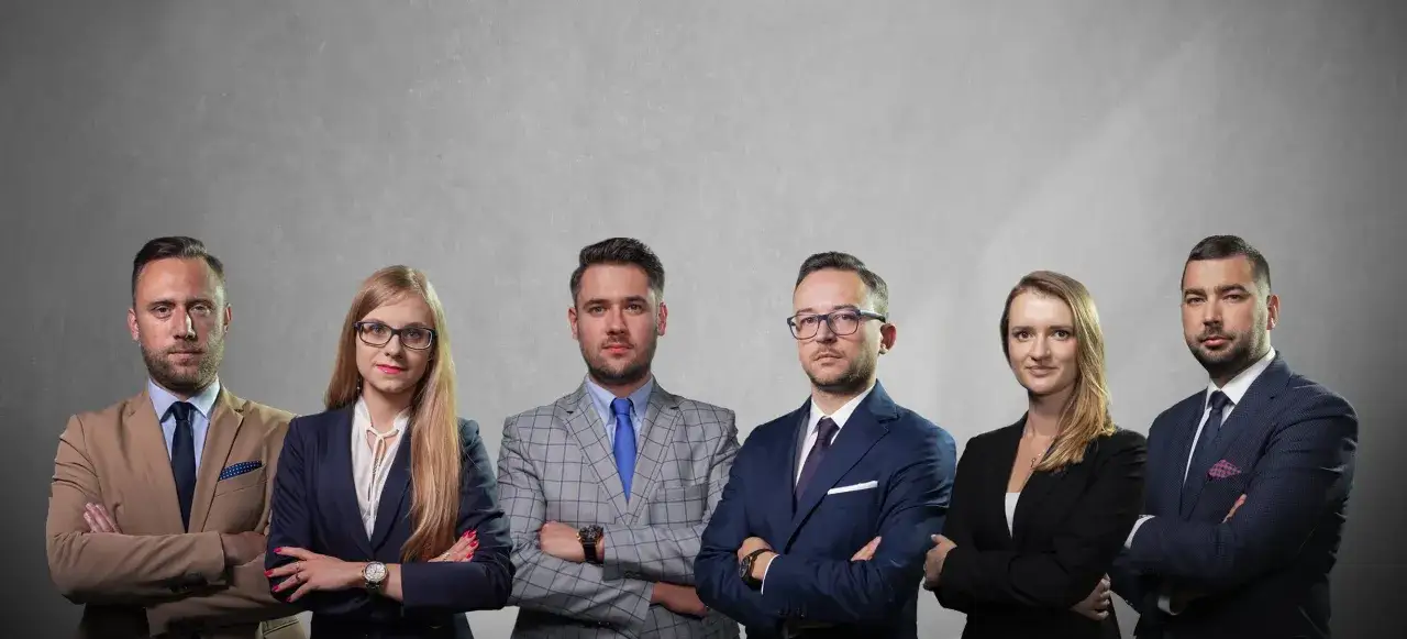 Sześć osób w garniturach, stojących z rękami skrzyżowanymi na piersi, na szarym tle.