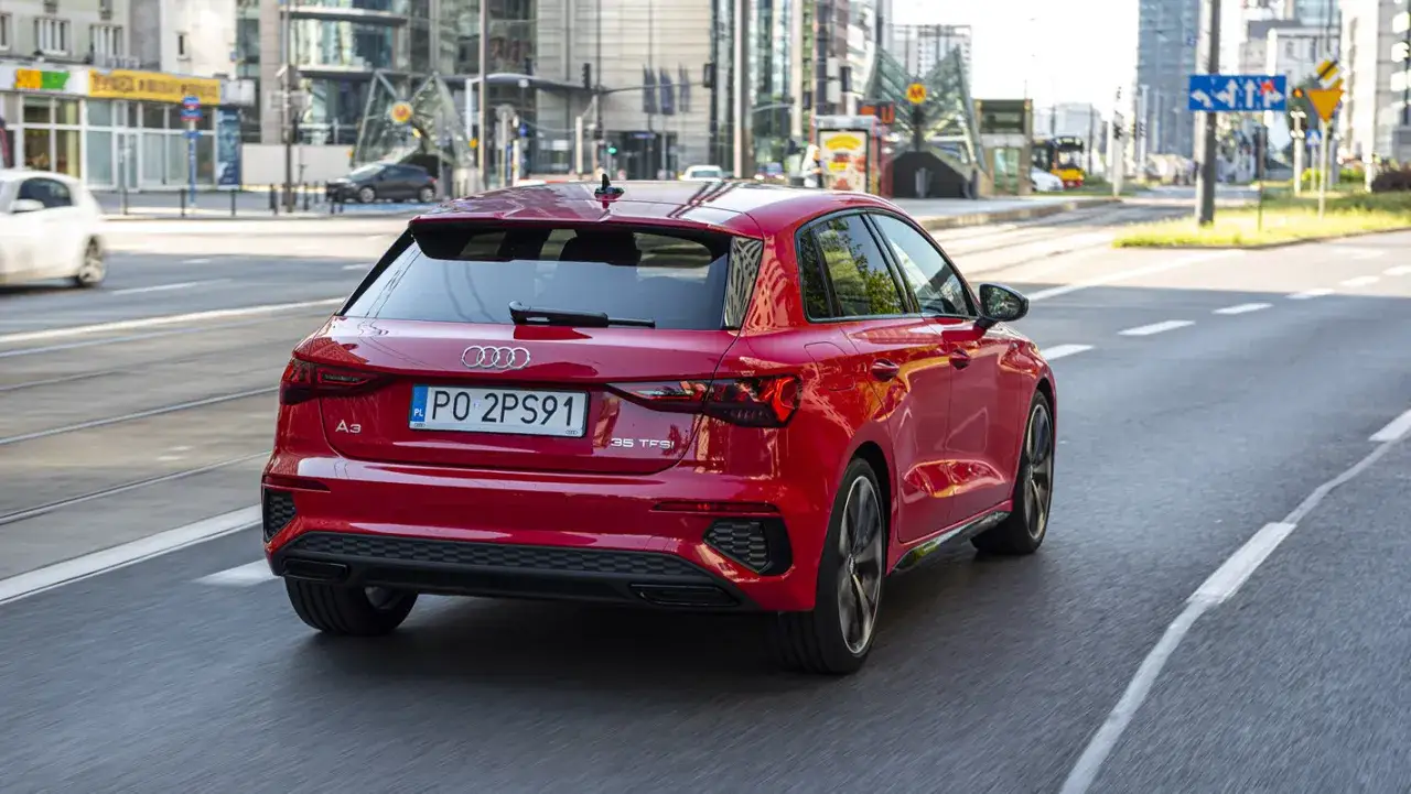 Czerwone Audi A3 kombi jedzie ulicą w mieście.