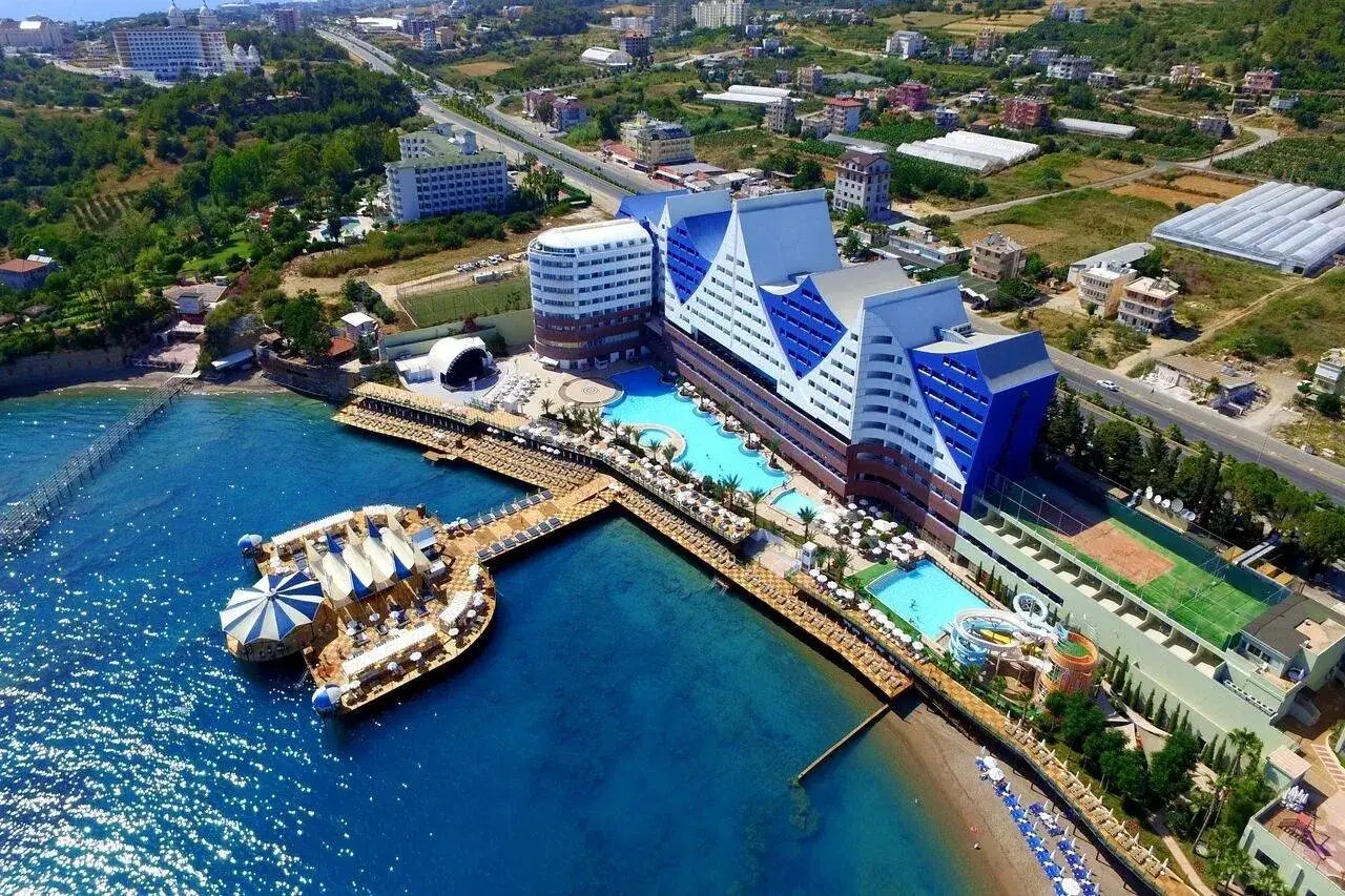 Widok z lotu ptaka na Orange County Resort Alanya z basenami, molo i plażą.