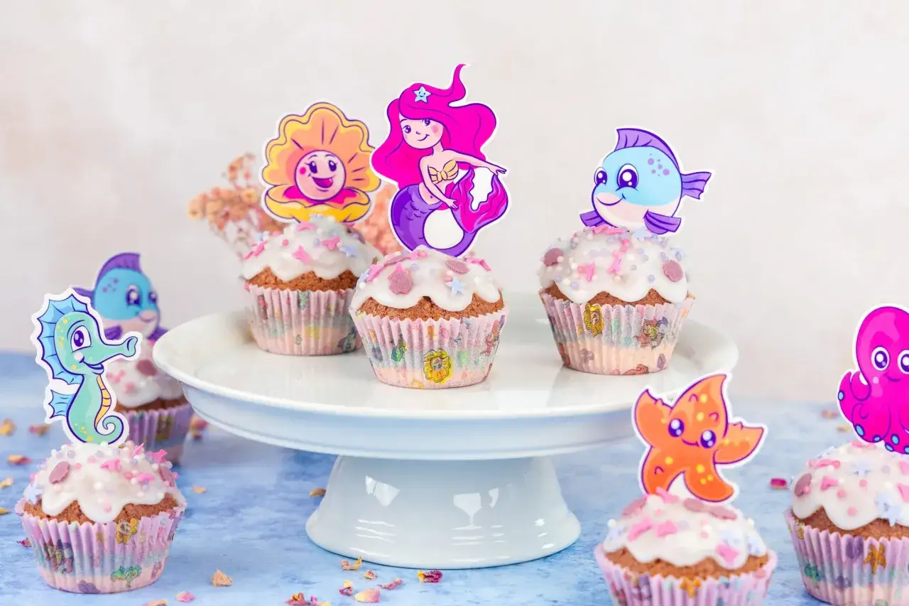 Meerjungfrau Muffins mit Seepferdchen, Fisch und Oktopus-Deko. Bunte Meeresbewohner zieren die süßen Leckereien.