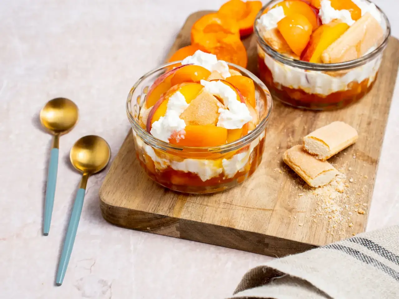 Deux coupes de tiramisu aux abricots, un d&eacute;licieux dessert de saison, garnies de cr&egrave;me fouett&eacute;e et de biscuits &agrave; la cuill&egrave;re.