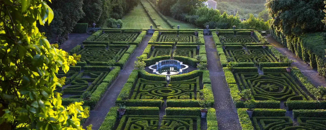 Giardini geometrici e fontana al Castello Ruspoli, un labirinto verde che incanta sotto il sole del mattino.