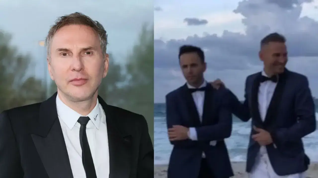 Krzysztof Gojdź w garniturze obok dwóch mężczyzn w smokingu na plaży.