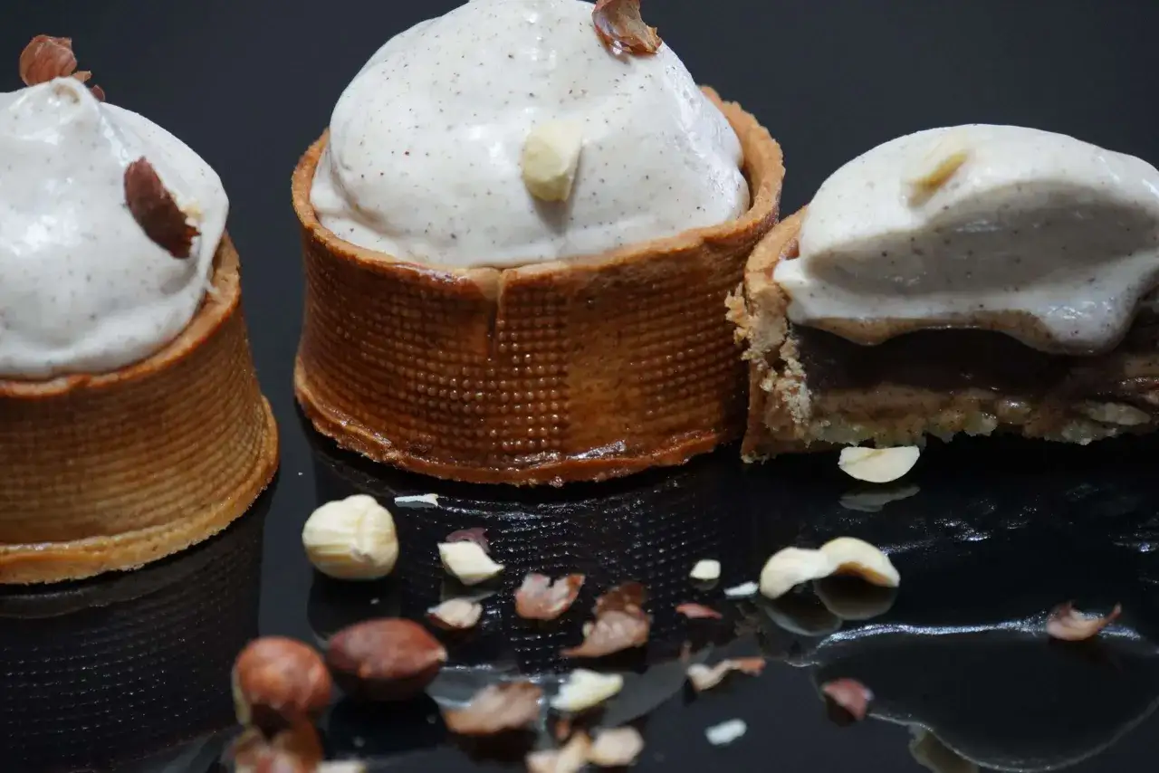 Trois tartelettes garnies d'une mousse l&eacute;g&egrave;re et parsem&eacute;es de noisettes concass&eacute;es. Le pralin&eacute; noisette est subtilement pr&eacute;sent.