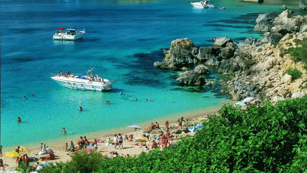 Malta plaże piaszczyste z turkusową wodą, łodziami i ludźmi odpoczywającymi na słońcu.