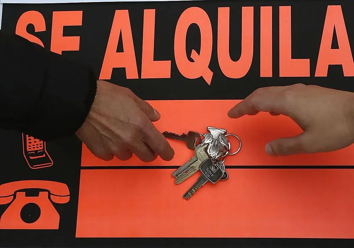 Manos intercambiando llaves frente a un cartel de
