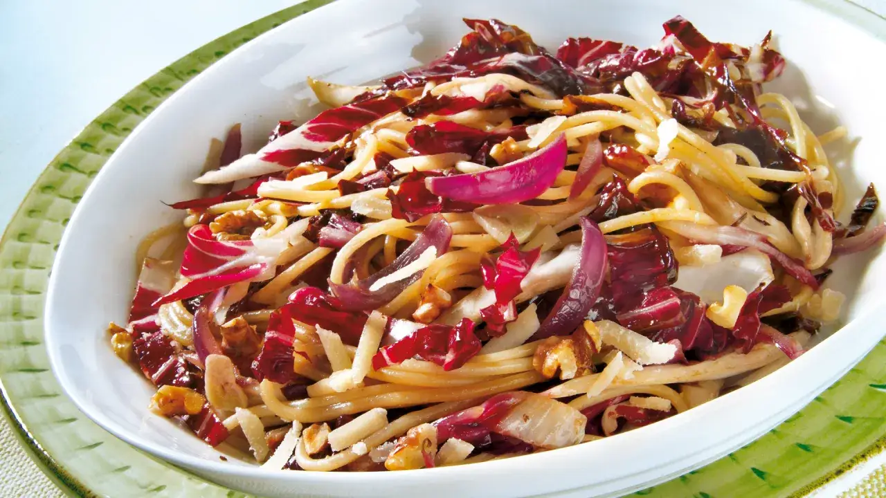 Ein k&ouml;stliches Radicchio-Rezept italienisch: Spaghetti mit Radicchio, N&uuml;ssen und Parmesan in einer wei&szlig;en Sch&uuml;ssel.