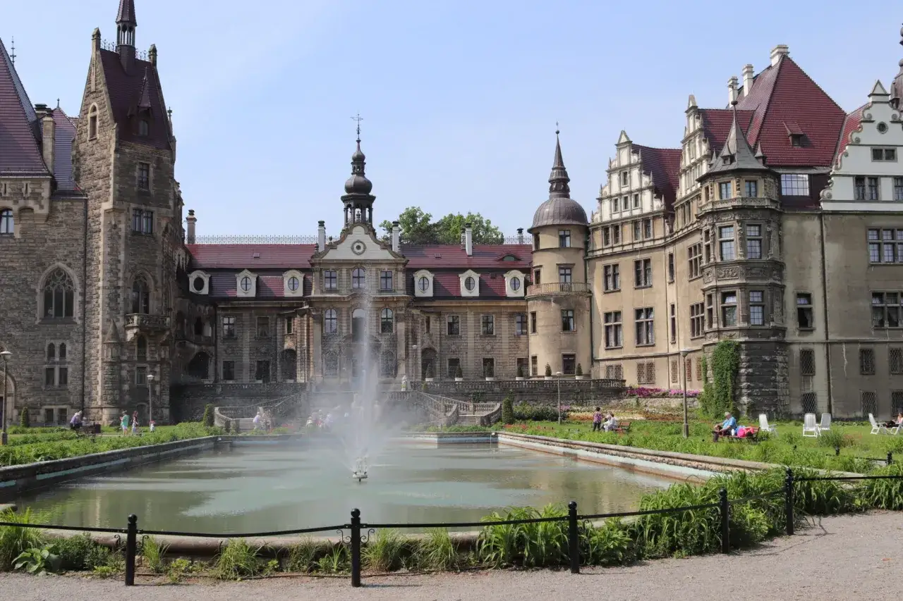 Pałac w Mosznej, z fontanną przed nim, zachwyca architekturą.