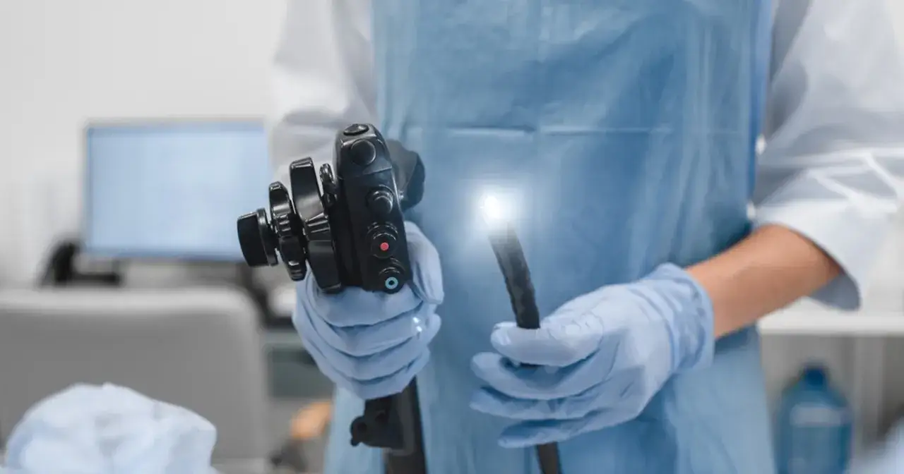 Lekarz w rękawiczkach trzyma endoskop, narzędzie kluczowe w diagnostyce i najnowszych metodach leczenia raka jelita grubego.