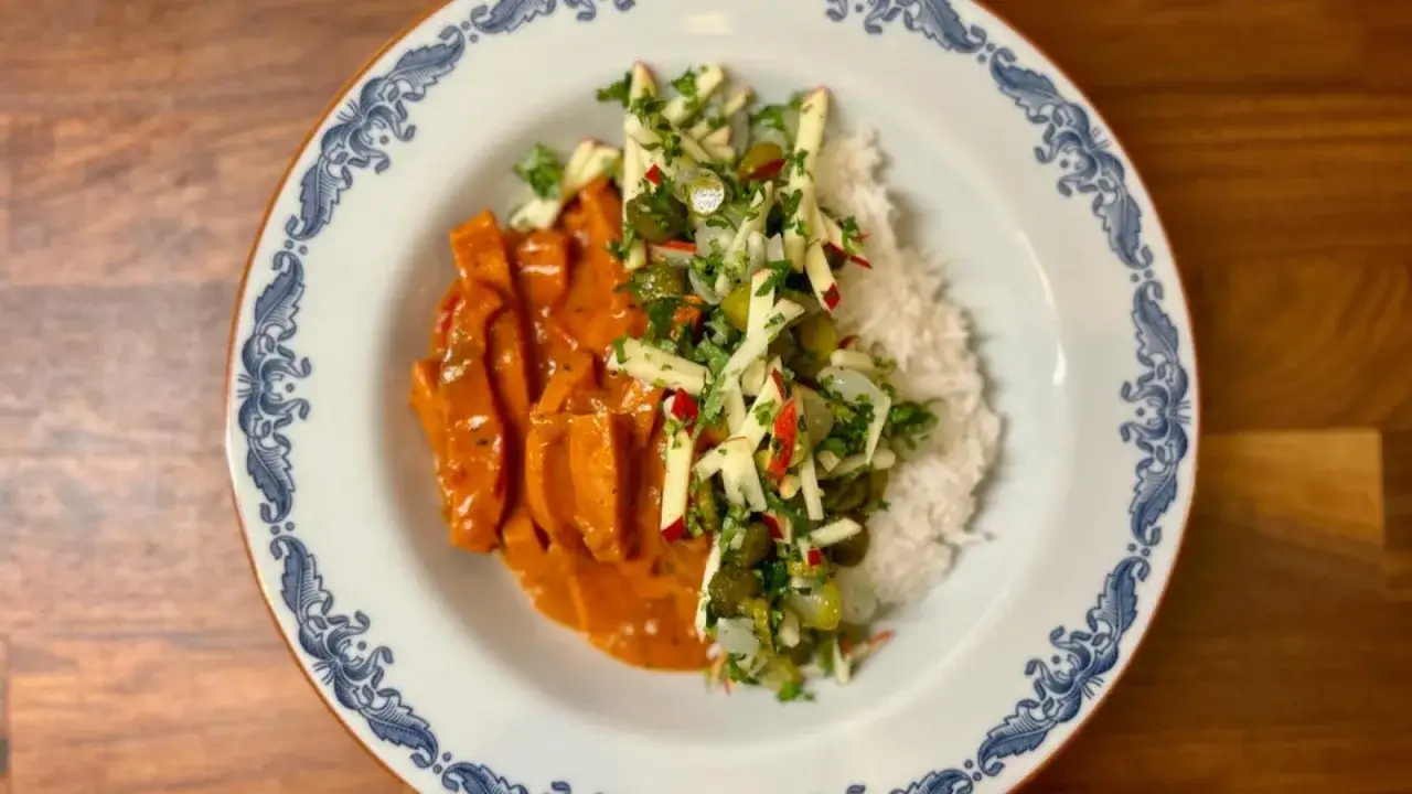 En tallrik med krämig korv stroganoff, ris och en fräsch äppel- och gurksallad. Ett perfekt recept för godaste korv stroganoff!
