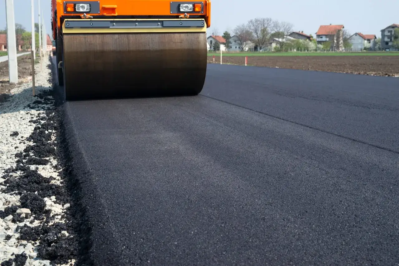 Walec drogowy ugniata świeży asfalt. Zastanawiasz się, ile kosztuje tona asfaltu na gorąco?