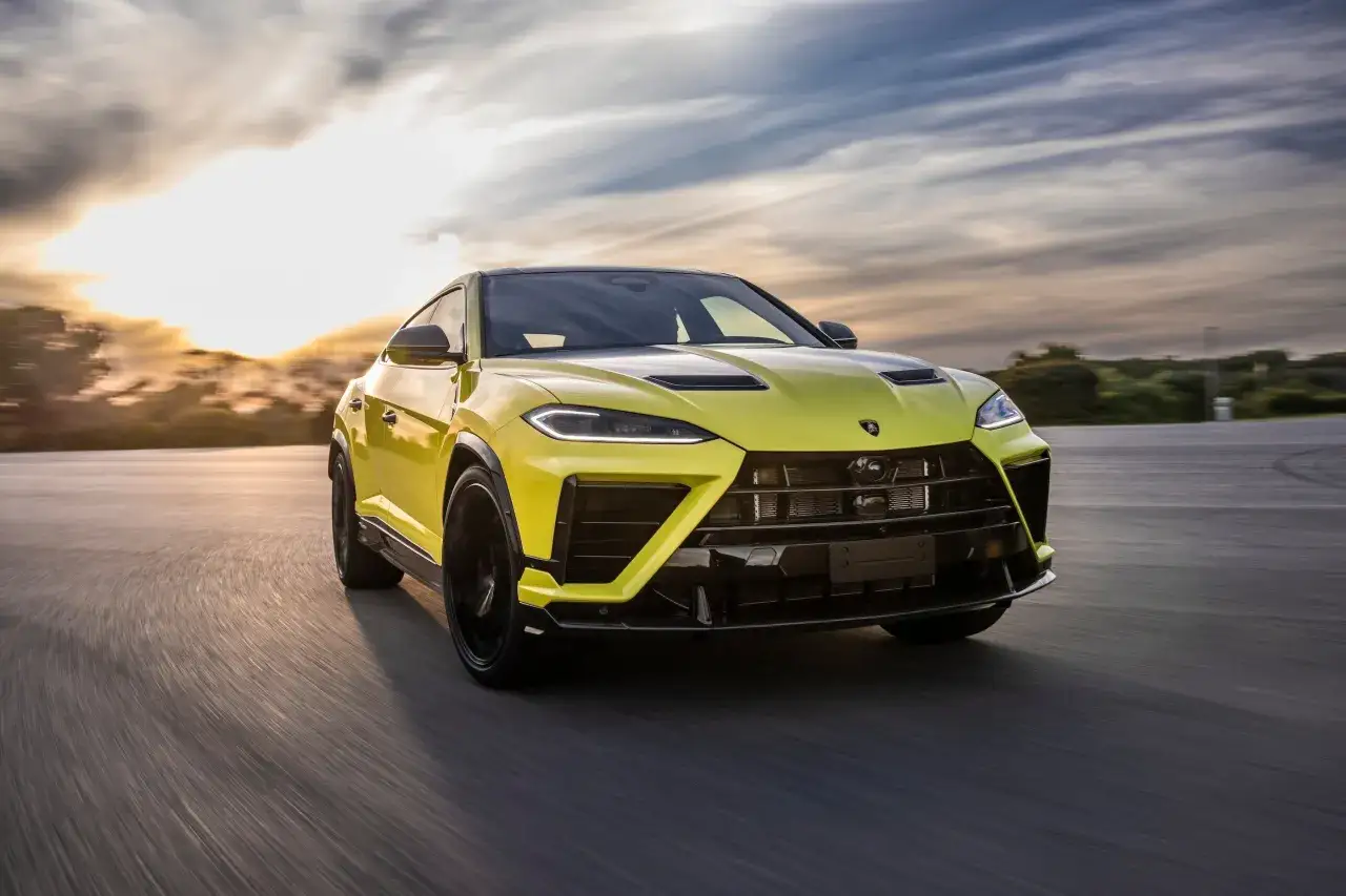 Żółte Lamborghini Urus pędzi po drodze podczas zachodu słońca. Zastanawiasz się, ile kosztuje Lamborghini Urus?