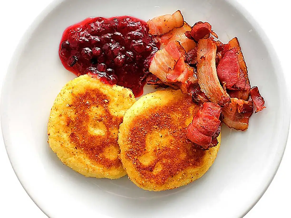 Två gyllene potatisbullar med lingonsylt och knaperstekt bacon. Ett klassiskt potatisbullar recept som passar perfekt till helgfrukosten.