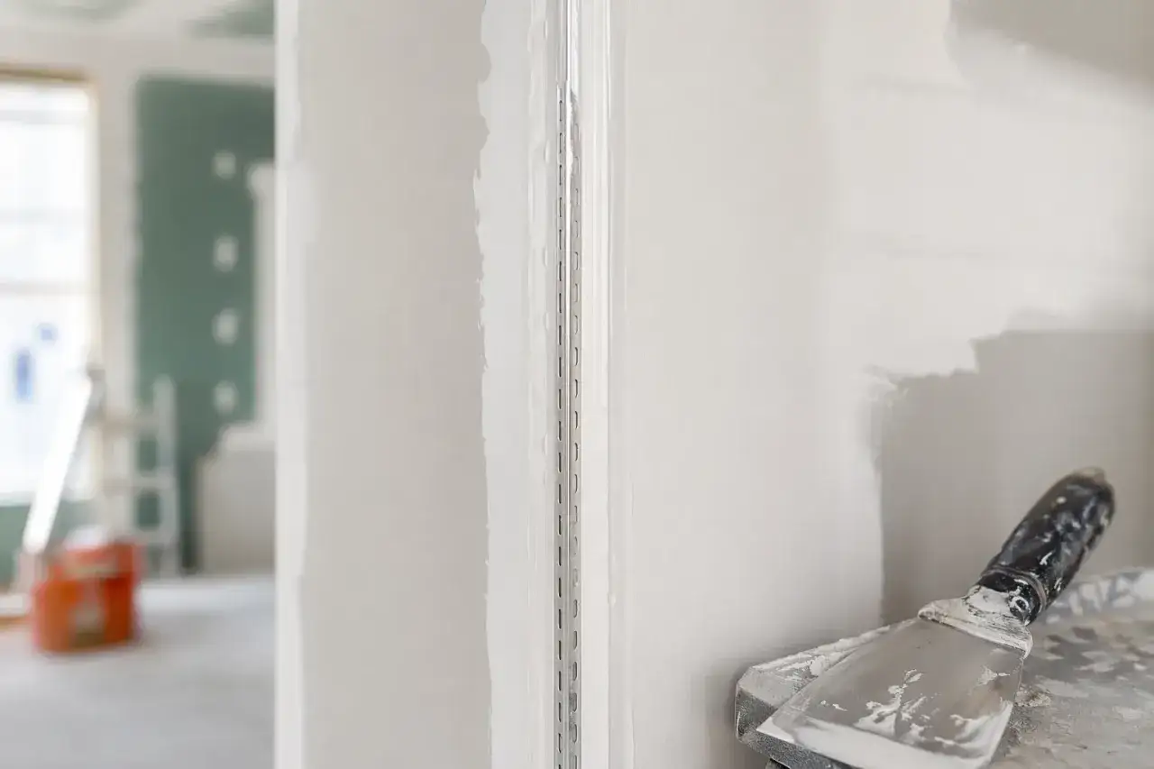 Dettaglio di un angolo con giunti cartongesso in fase di finitura, con spatola e stucco in primo piano.