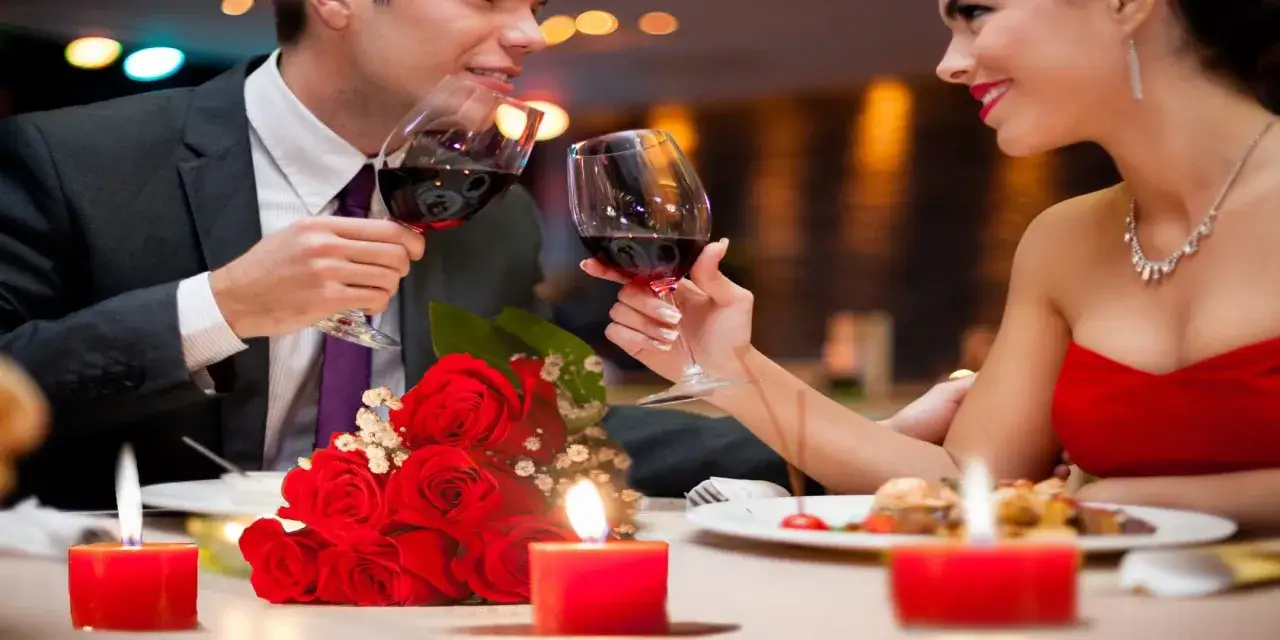 Coppia brinda con vino rosso, candele e rose rosse. Il mio San Valentino in inglese, una serata romantica.