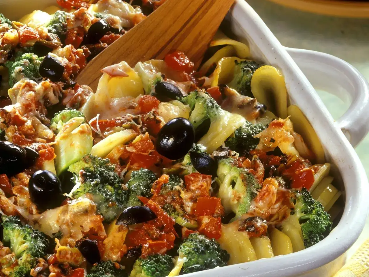 Ein k&ouml;stlicher vegetarischer Auflauf mit Brokkoli, Tomaten, Oliven und geschmolzenem K&auml;se, bereit zum Servieren.