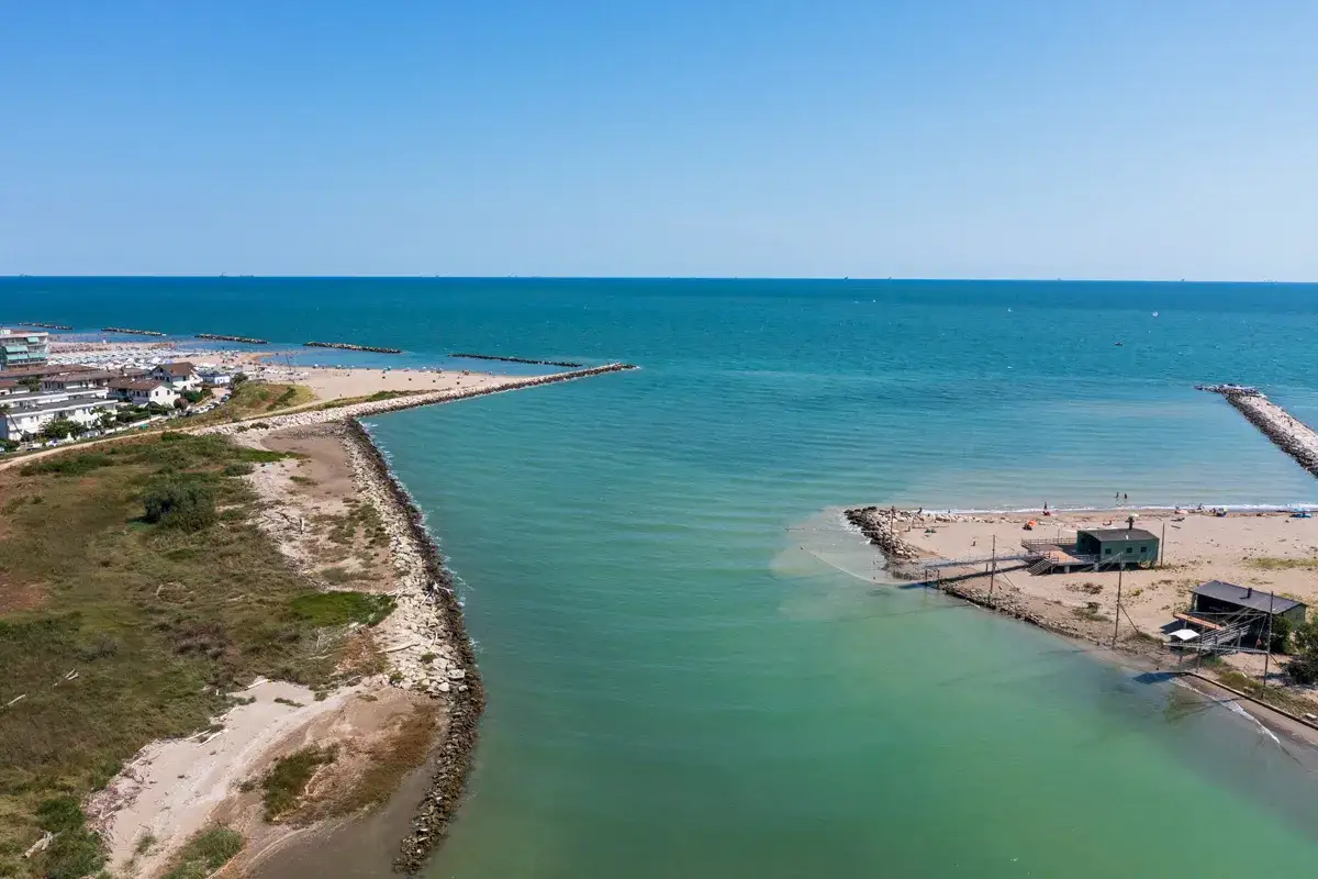 Vista aerea del lido di Savio, con il mare turchese che lambisce la costa e il centro storico sullo sfondo.