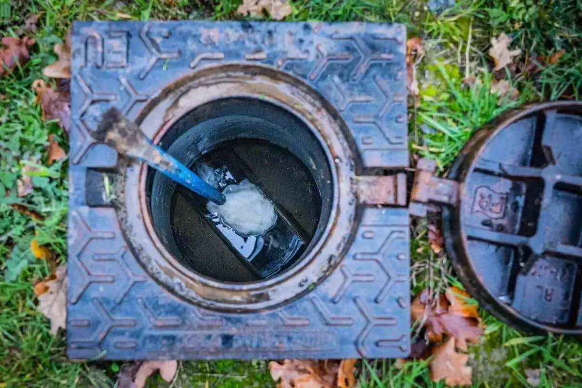 Un outil bleu tente de d&eacute;gager un bouchon dans un regard d'&eacute;gout. Que faire en cas de tout &agrave; l'&eacute;gout bouch&eacute; ?