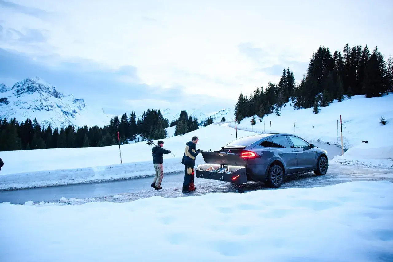 Tv&aring; m&auml;n packar en Thule Touring Sport-box p&aring; en bil i sn&ouml;ig bergsmilj&ouml;.