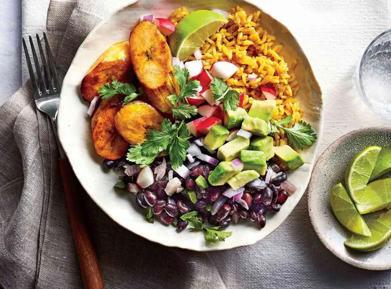 Bunte Bowl mit Reis, schwarzen Bohnen, Kochbananen, Avocado und Radieschen. Perfekt für clean eating rezepte.