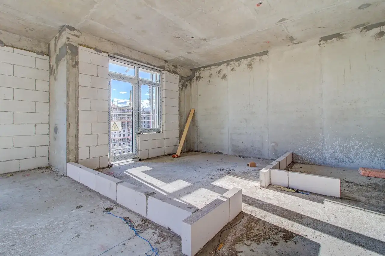 Einblick in den Rohbau: weiße Ziegelsteine bilden die Wände, ein Fenster ist eingesetzt. So baut man ein Haus, Schritt für Schritt.