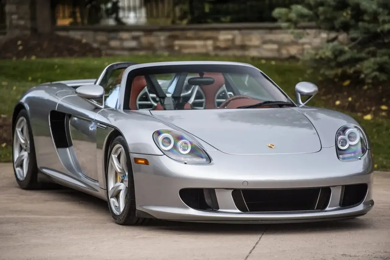 Srebrny Porsche Carrera GT z rudymi siedzeniami, gotowy do jazdy.