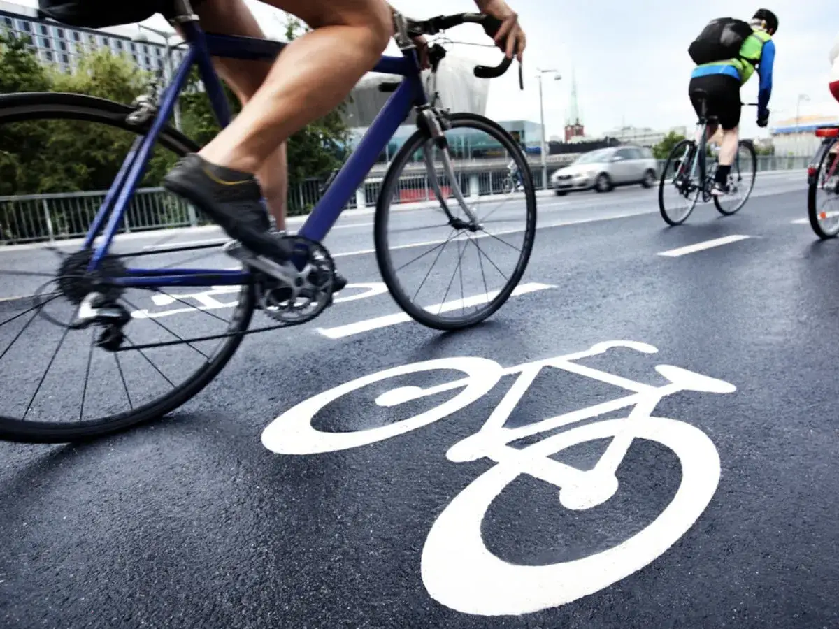 Kolarze na ścieżce rowerowej, z symbolem roweru na asfalcie. Czy śledzą trasę na komoot czy strava?