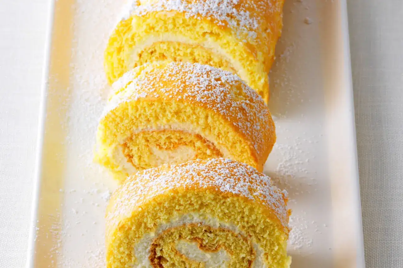 Saftige Zitronenrolle, bestäubt mit Puderzucker. Ein köstliches Rezept für Sonnenschein auf dem Teller.