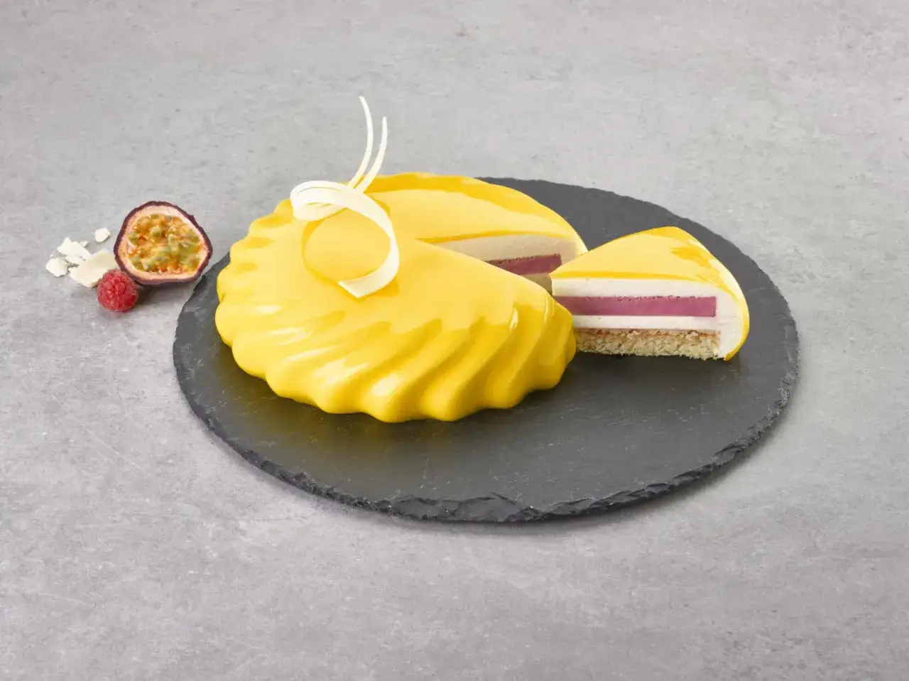 Gâteau aux couches de fruits et crème, recouvert d'un glacage miroir jaune éclatant. Une tranche révèle un cœur rose.