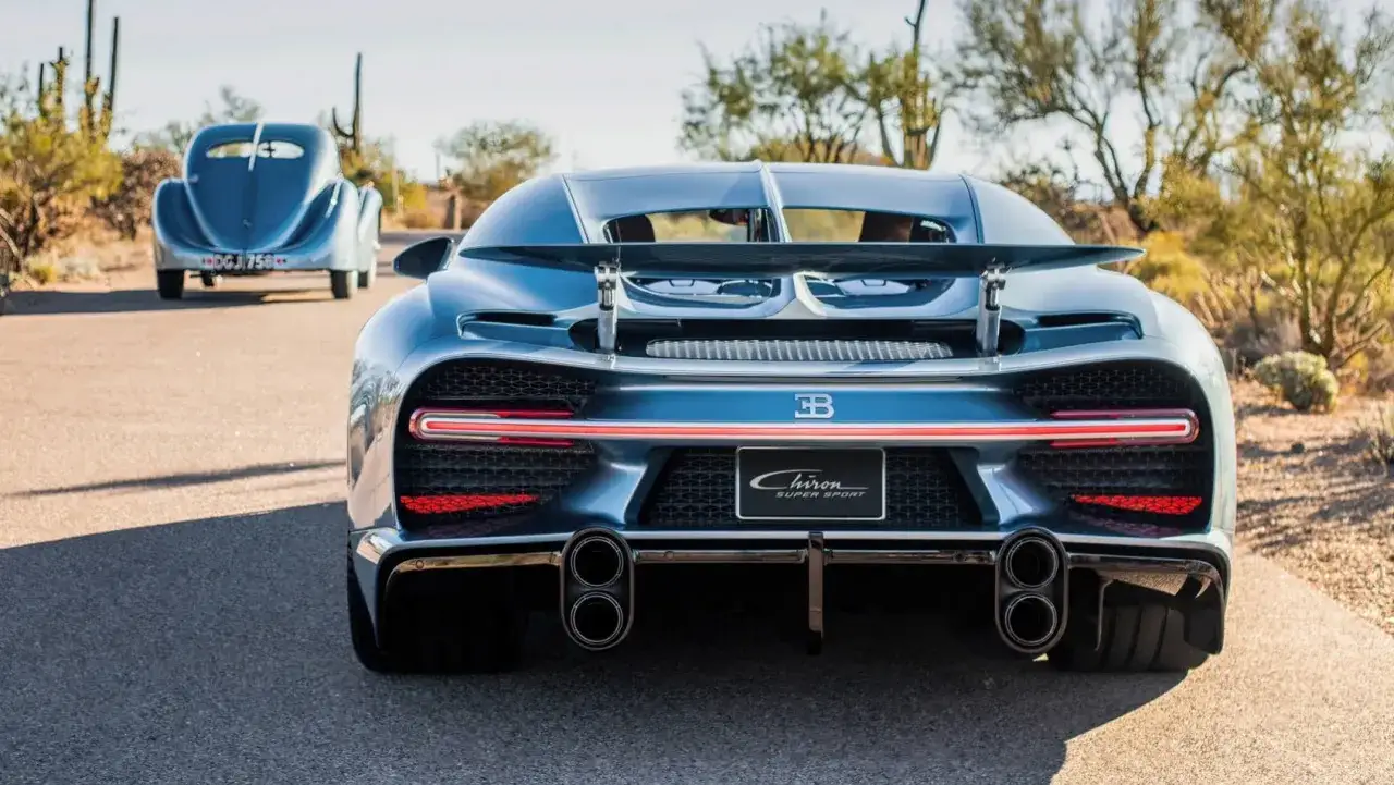 Niebieski Bugatti Chiron Super Sport z tyłu, obok klasycznego Bugatti.