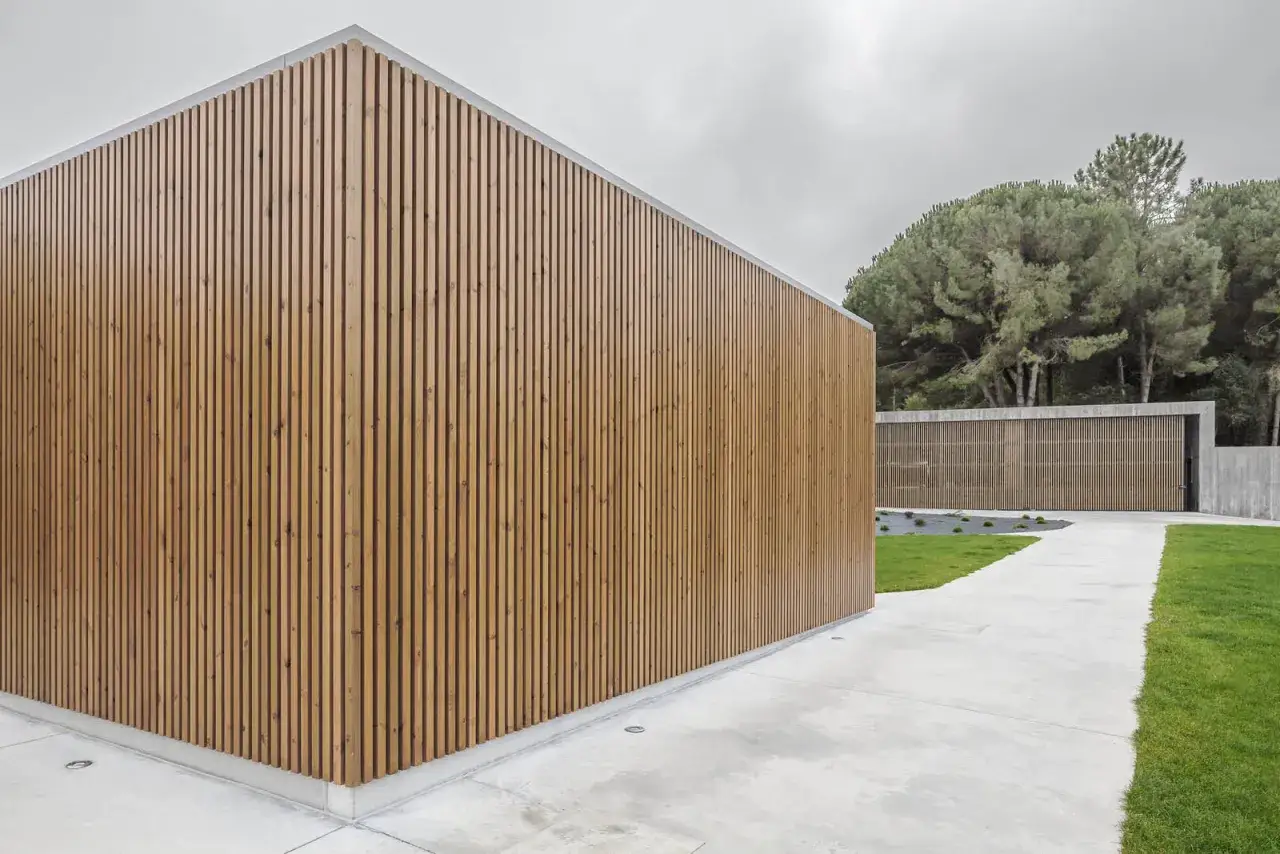 Edificio moderno con revestimiento de lamas de madera, la mejor madera para exterior, rodeado de c&eacute;sped y &aacute;rboles.