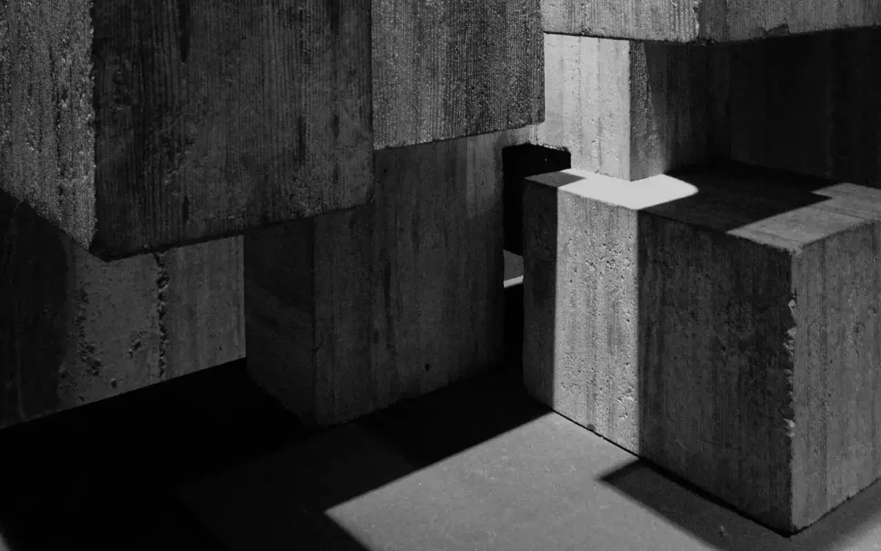 Betonowe bloki tworzą abstrakcyjną kompozycję. Światło i cień podkreślają ich teksturę, tworząc grę form. To jakby fragment architektury, może cem iii.