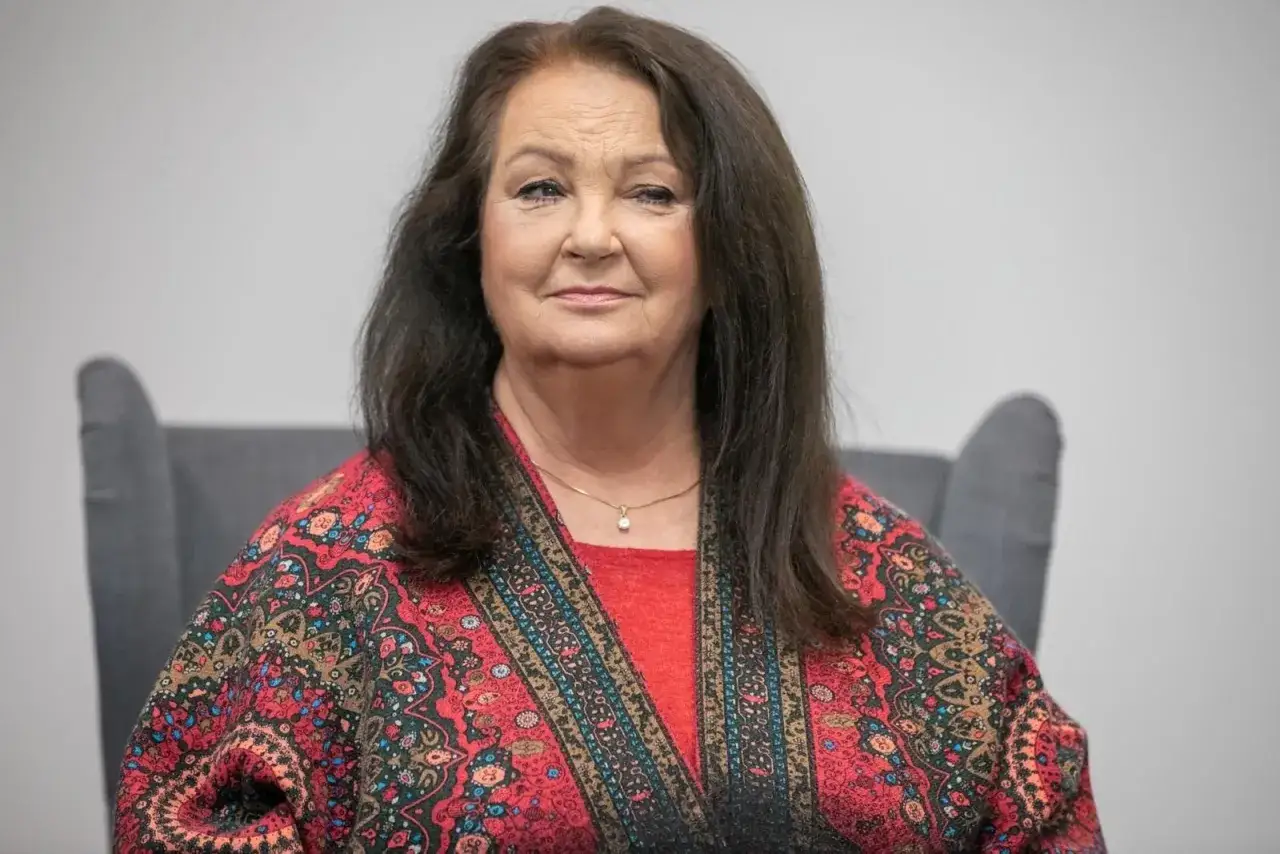 Anna Dymna w kolorowym stroju, siedzi w fotelu. Czy Anna Dymna ma dzieci? To pytanie nurtuje wielu fanów.