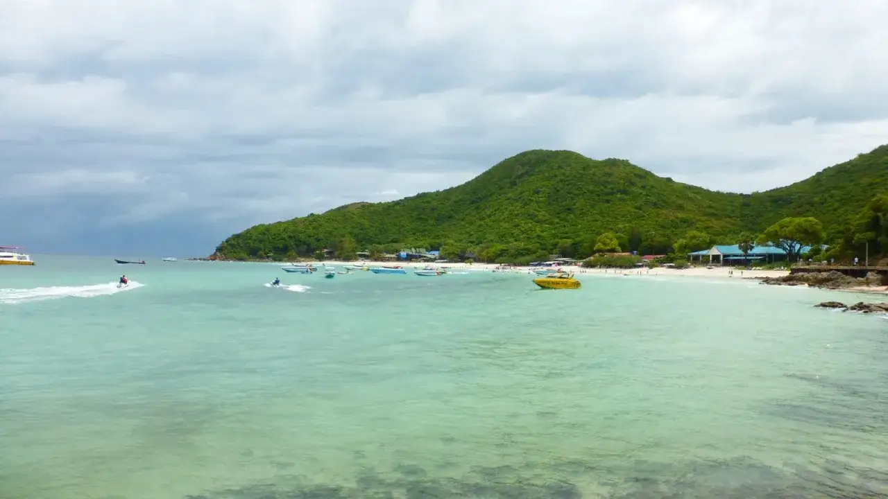 Wodne skutery i łodzie na turkusowym morzu, zielone wzgórza w tle. Idealne wakacje Pattaya!