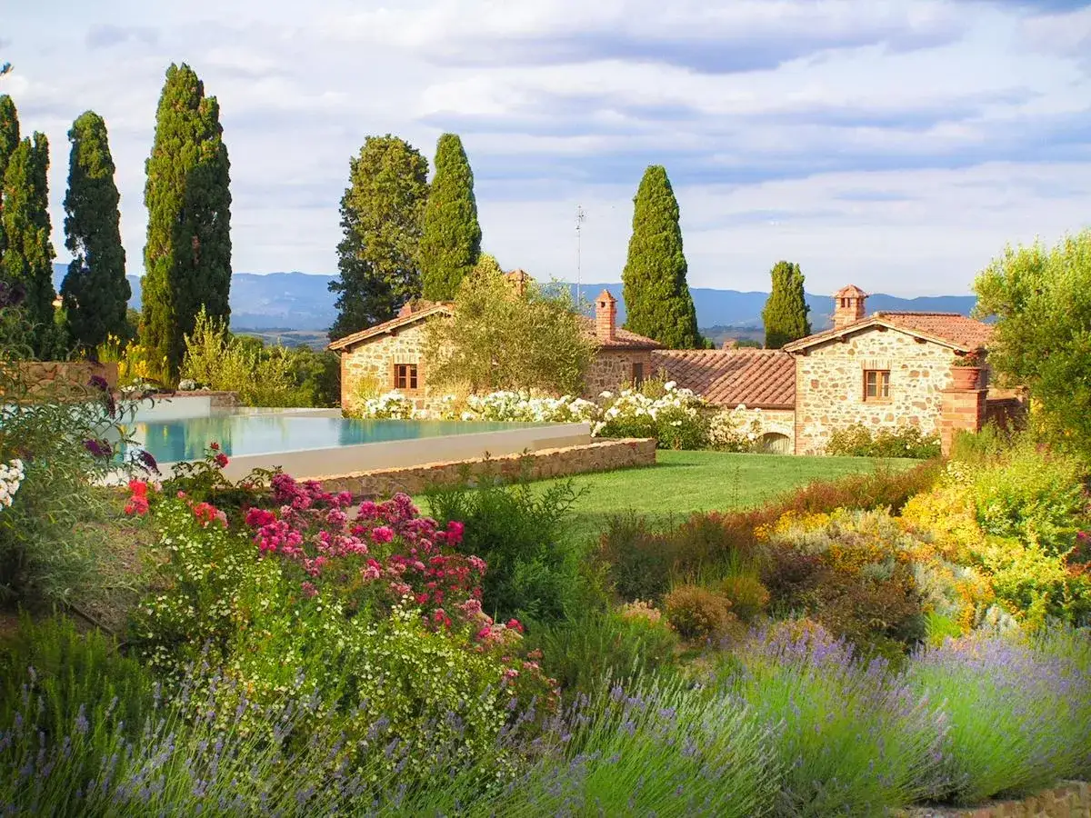 Un sogno di vacanze in Toscana dove andare: piscina, cipressi, casali in pietra e un giardino fiorito.