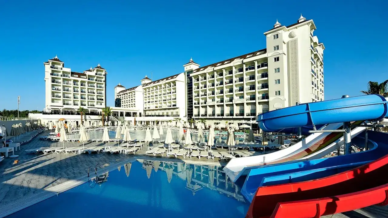 Starlight Resort Hotel: basen z wodnymi zjeżdżalniami i leżakami, otoczony białymi budynkami hotelowymi pod błękitnym niebem.