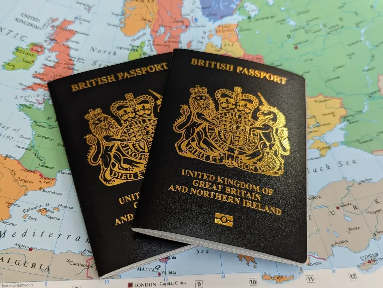 Dwa brytyjskie paszporty leżą na mapie Europy. Czy do UK potrzebny jest paszport? Tak, dla obywateli spoza strefy Schengen.