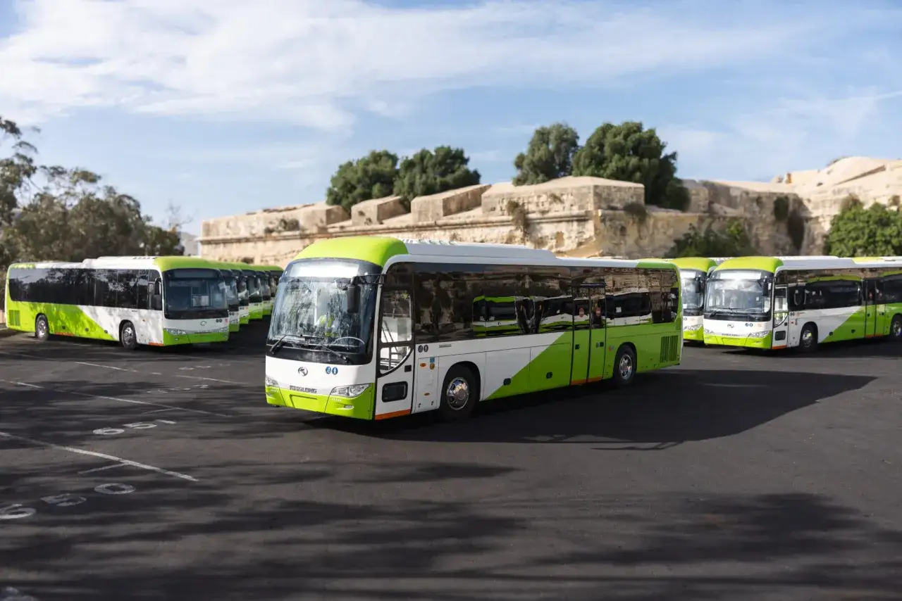Malta: zielono-białe autobusy czekają na pasażer&oacute;w na parkingu, gotowe do obsługi transportu z lotniska.