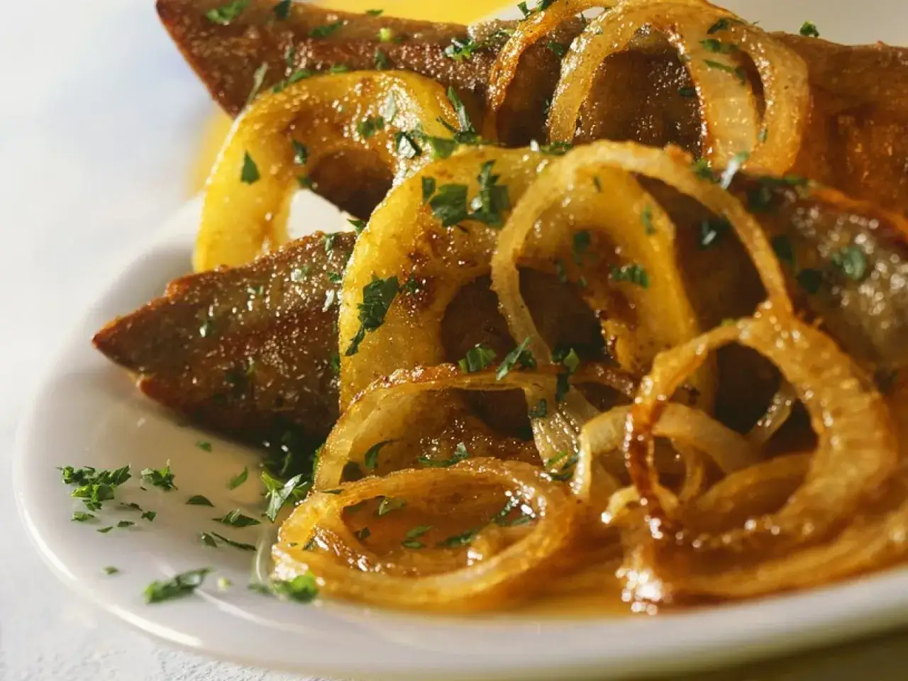 Gebratene Leber mit karamellisierten Zwiebelringen, bestreut mit Petersilie. So brate ich Leber f&uuml;r ein k&ouml;stliches Gericht.