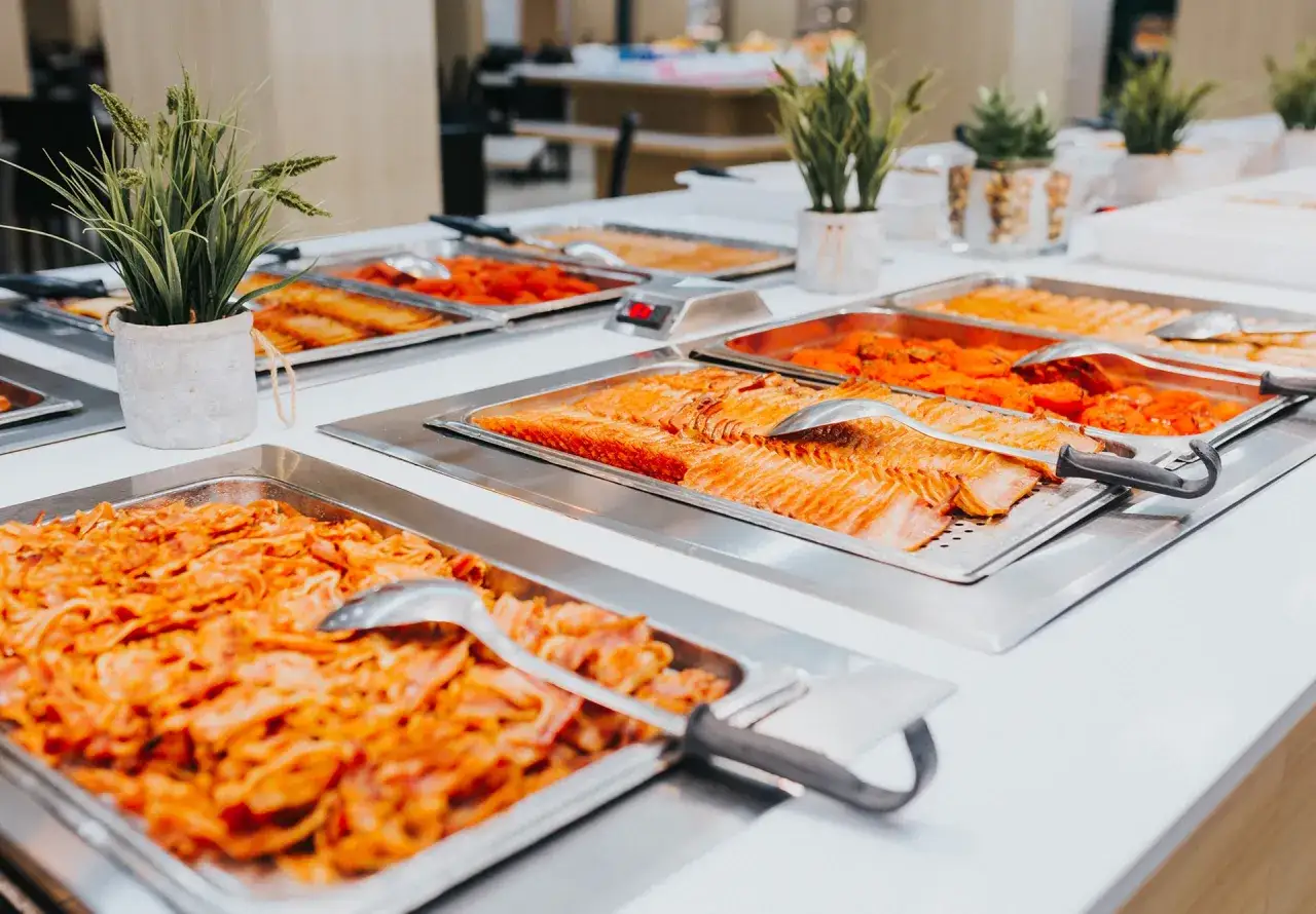 Bandejas de comida en un buffet, con salmón y otros platos de la quinta gama.