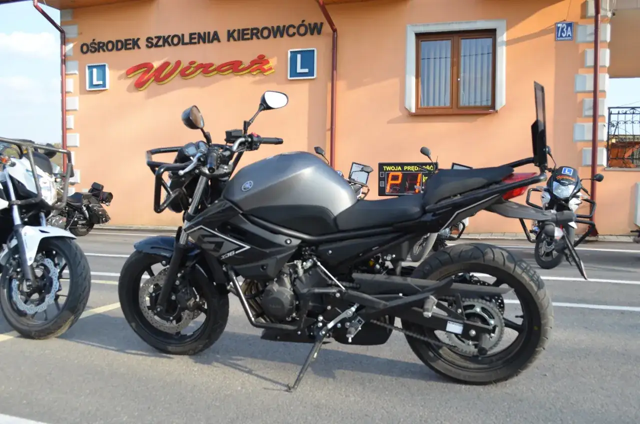 Szary motocykl Yamaha XJ6, idealny na egzamin kat A, stoi przed ośrodkiem szkolenia kierowców 