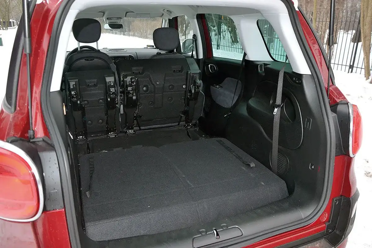 Przestrzeń bagażowa w czerwonym Fiat 500 L z rozłożonymi tylnymi siedzeniami, gotowa na podróż.