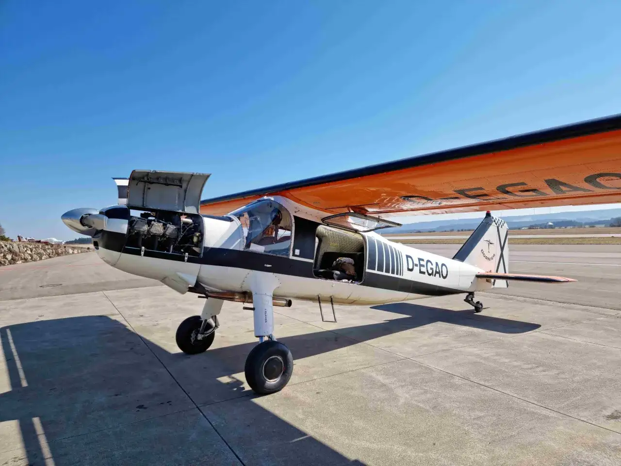 Kleines Flugzeug D-EGAO mit geöffneter Motorhaube und Tür auf dem Rollfeld. Bereit für den Flug am 27.