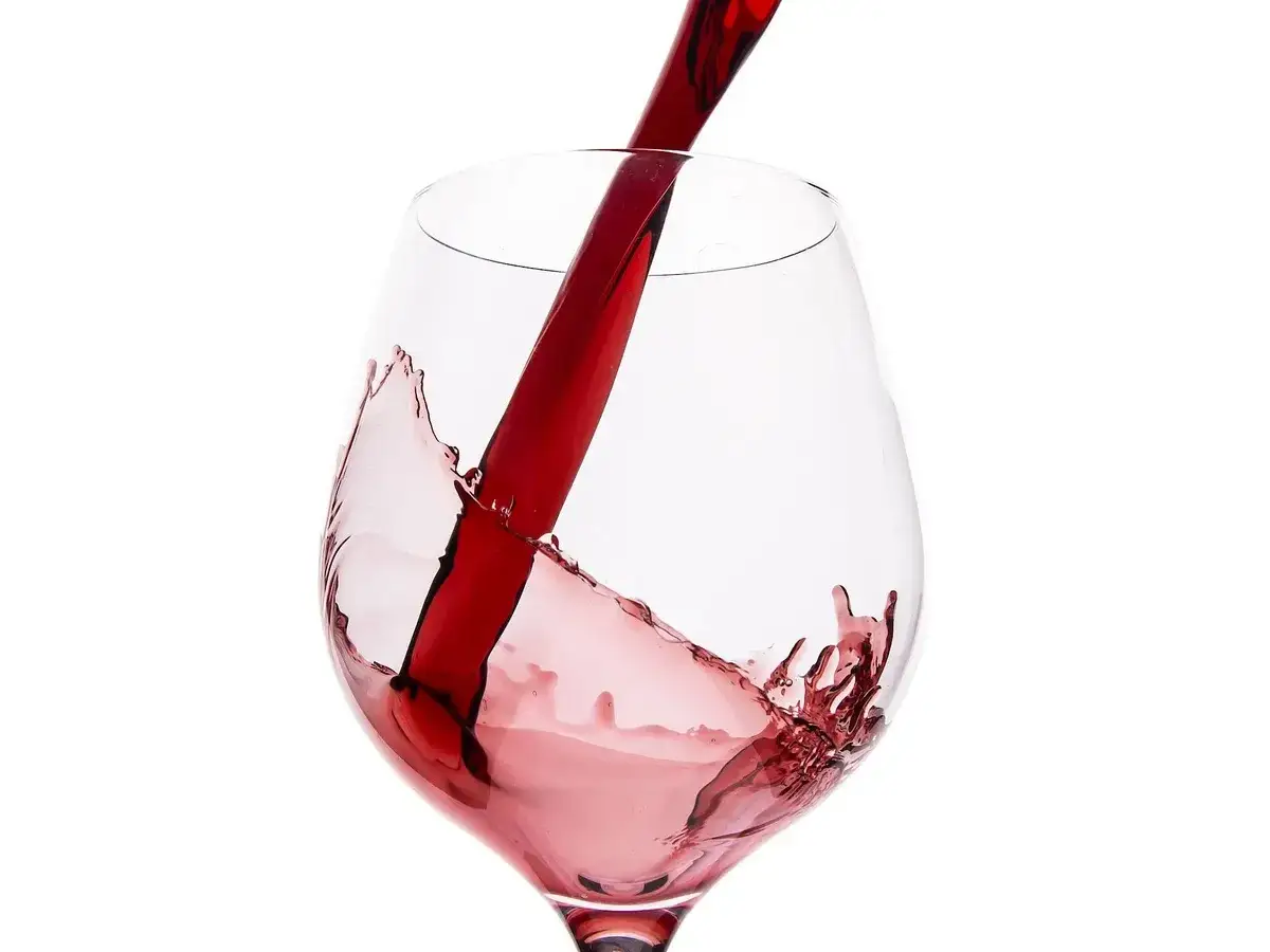 Rotwein wird in ein Glas gegossen, wobei Spritzer entstehen. So lagert man offenen Rotwein.
