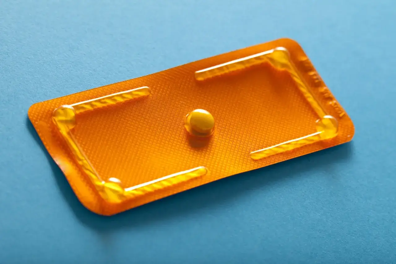 Pillola del giorno dopo: quando prenderla per una protezione efficace. Una singola pillola in blister arancione su sfondo blu.