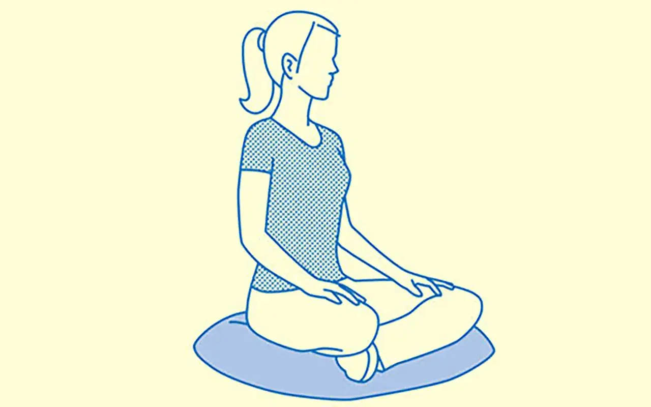 Donna in posizione meditativa, con gambe incrociate su un cuscino. La sua postura e respirazione sono rilassate, pronta per la concentrazione.
