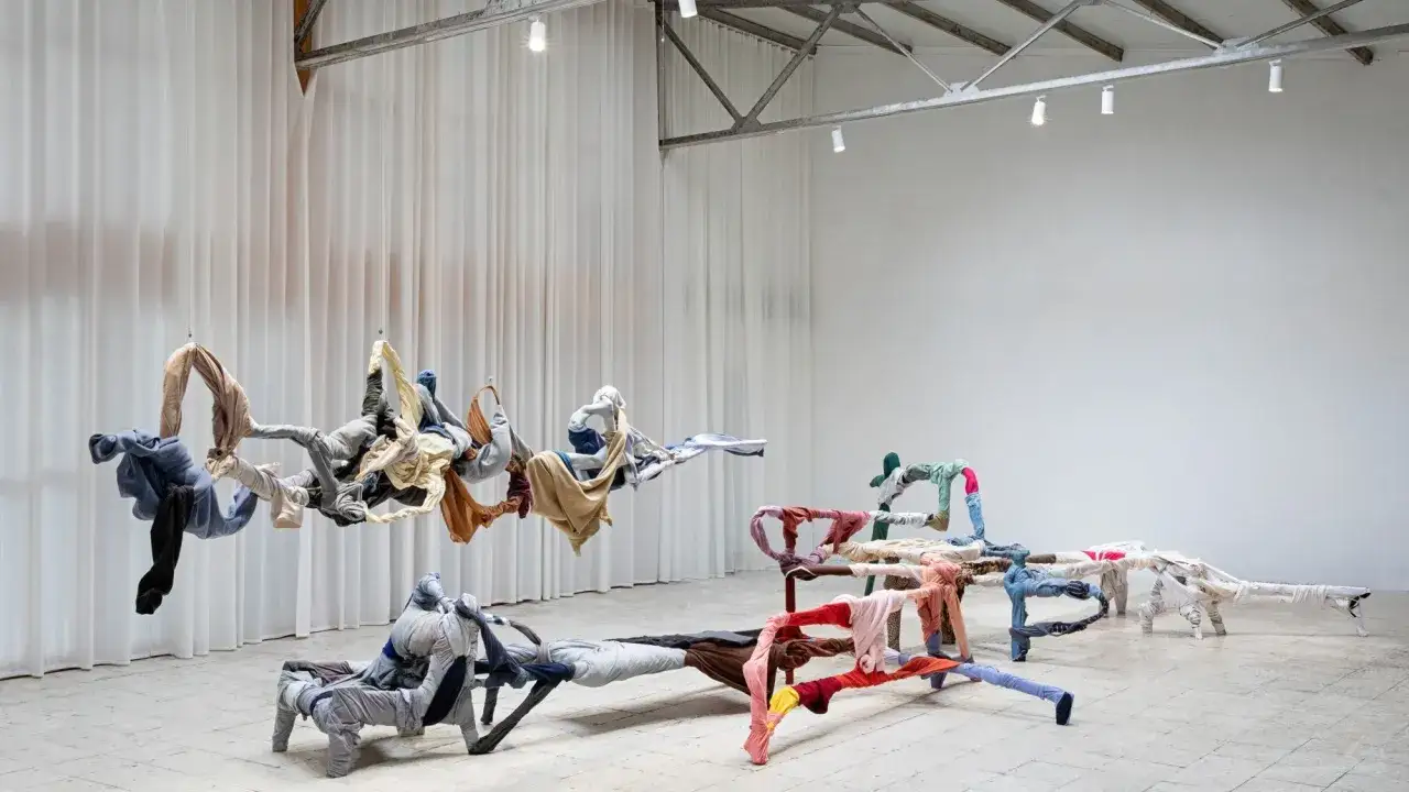 Instalación de ropa suspendida y en el suelo, un ejemplo de lo que es el arte contemporáneo, que explora la forma y el color.
