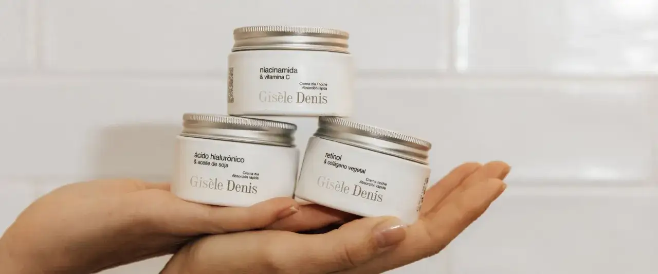 Hände halten drei Cremetiegel. Einer mit niacinamide & vitamina C, einer mit ácido hialurónico und einer mit retinol.