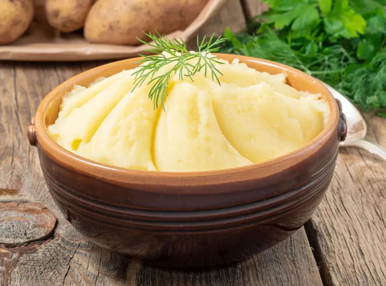Puszyste puree ziemniaczane w glinianej misce, ozdobione gałązką koperku. Idealny dodatek do obiadu, dowiedz się, jak zrobić puree!